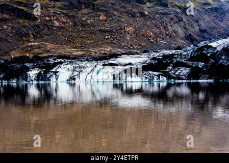 Solheimajokull glacier covered in soot from previous eruptions with the glacial lake descending from the volcano near Vik in Iceland Stock Photo