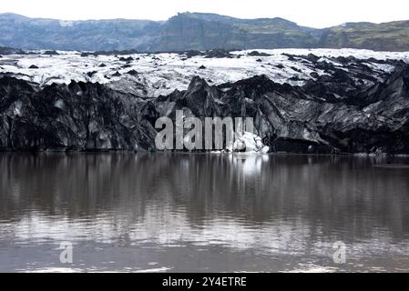 Solheimajokull glacier covered in soot from previous eruptions with the glacial lake descending from the volcano near Vik in Iceland Stock Photo