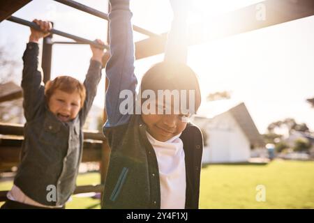 Children, portrait and swing on monkey bars, playing together and friends at park for fun. Kids, boys and games on jungle gym playground for childhood Stock Photo