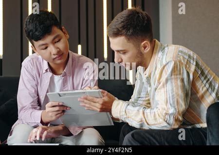 Collaborating on Digital Tablet in Modern Office Setting Stock Photo