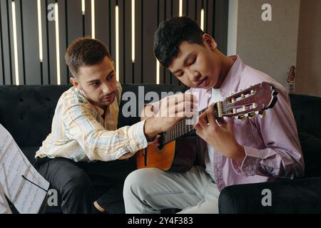 Teacher Guiding Student on Playing Acoustic Guitar Stock Photo