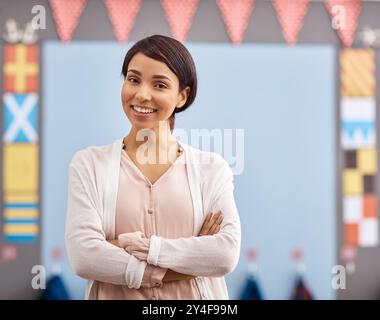 Portrait, teacher and woman with arms crossed, education and proud of teaching, knowledge or smile. School, professional and person in elementary Stock Photo