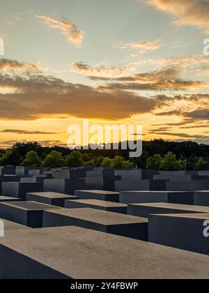 BERLIN, GERMANY - JULY 20, 2023: Panoramic view of famous Jewish Holocaust Memorial near Brandenburg Gate in golden evening light with blue sky at sun Stock Photo