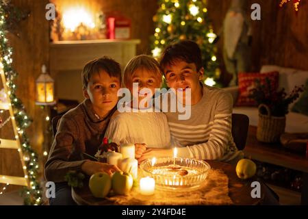 Three children, lighting candles in a nutshell, czech Christmas traditions, decorated room, family traditions Stock Photo