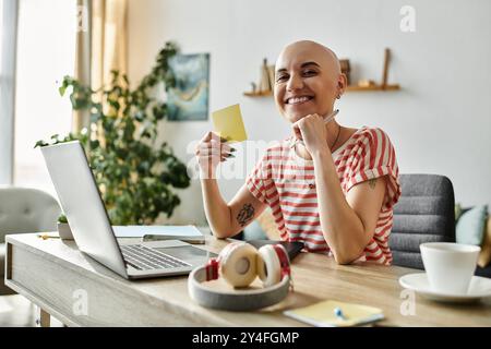 A joyful bald woman engages with her workspace, surrounded by plants and a laptop. Stock Photo