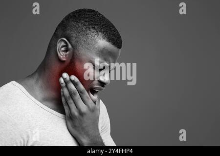Young man having acute toothache, holding his jaw Stock Photo