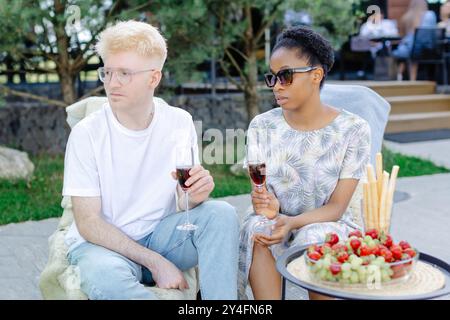 Friends rest together, drink wine, talk to each other on a picnic. Stock Photo