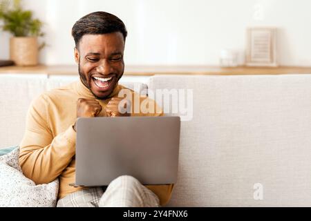 Happy Black Guy Shaking Fists Looking At Laptop At Home Stock Photo
