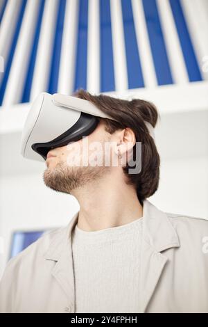 Vertical side view portrait of man wearing VR headset in minimal modern art museum setting Stock Photo