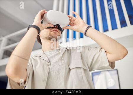 Low angle portrait of man wearing VR headset in modern art museum and looking at digital artwork, copy space Stock Photo