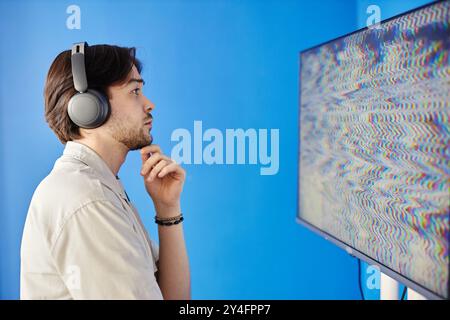 Minimal side view portrait of man wearing headphones looking at TV screen with static while visiting modern visual art exhibition, copy space Stock Photo