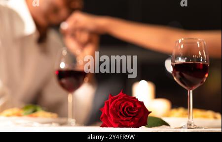 Red Rose Lying On Table, Man Kissing Woman's Hand Indoor Stock Photo
