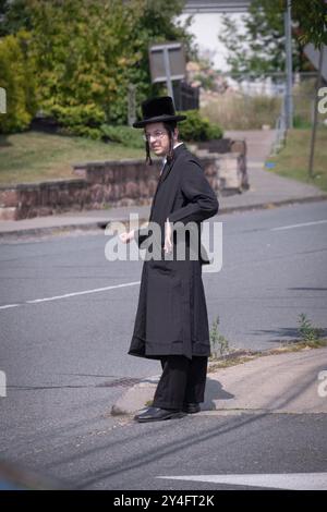 An orthodox young man with long curly peyus sticks his thumb out to hitchhike a ride in a mostly Jewish neighborhood in Rockland County, New York. Stock Photo