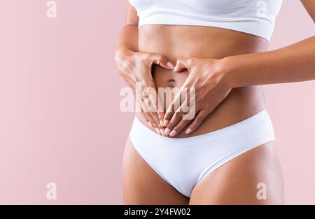 Cropped of woman making heart shape with hands over belly Stock Photo