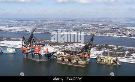 Heerema is active in the offshore wind and oil industry and known, among other things, for oil platforms and drilling rigs. The largest crane ship in the world, the Sleipnir, will be in the port of Rotterdam during the winter of 2020 and 2021 alongside its sister, the Thialf. Both for maintenance in the Calandkanaal, Rozenburg. In the background a beautiful snowy landscape netherlands out - belgium out Stock Photo