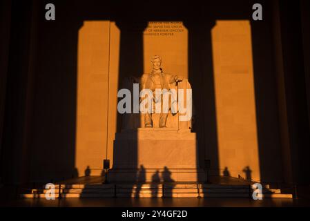 WASHINGTON DC, United States — The statue of Abraham Lincoln inside the Lincoln Memorial is illuminated by natural golden sunlight just after sunrise. This lighting effect, visible around the spring and fall equinox, enhances the monument's grandeur as the sun shines through the eastern entrance. The Lincoln Memorial, located on the National Mall, is one of the most iconic monuments in the United States. NB: The color and lighting are natural. Stock Photo