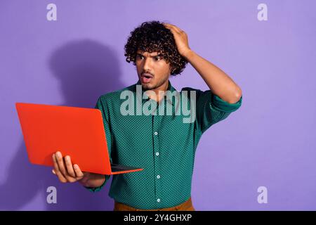 Photo of mexican funny guy with wavy haircut wearing green casual shirt holding laptop confused code crashed isolated on violet color background Stock Photo