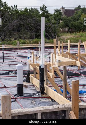 Trenches in the sand for plumbing and drain pipework with waterproofing and reinforcing steel for base of the foundation slab. Stock Photo