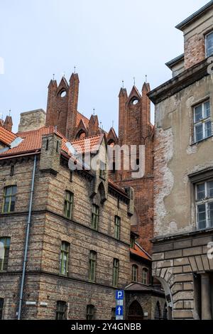 Gothic-style architecture of historic buildings in Gdansk, Poland, featuring brick facades and pointed arches against a cloudy sky. Stock Photo