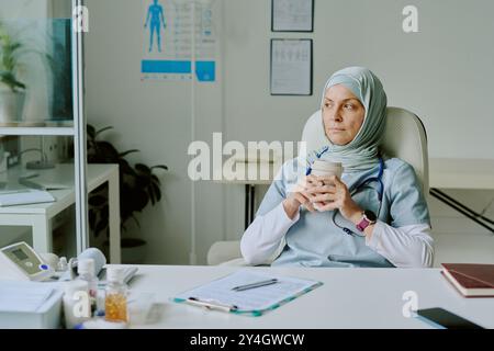 Medical Professional Drinking Coffee in Hospital Office Stock Photo