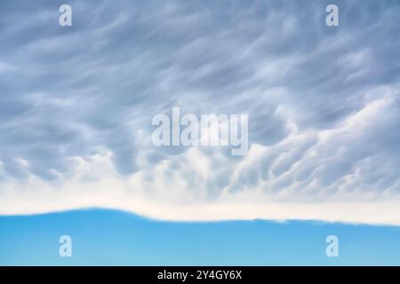 Mammatus clouds over a clear sky in horizontal format. End of the storm Stock Photo
