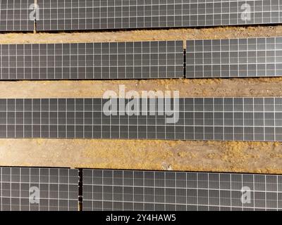 A drone captures an aerial view of rows of solar panels installed in a rural field, showcasing sustainable energy solutions for a greener future Stock Photo