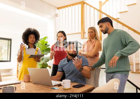 Discussing project, diverse group of friends collaborating around laptop at home Stock Photo