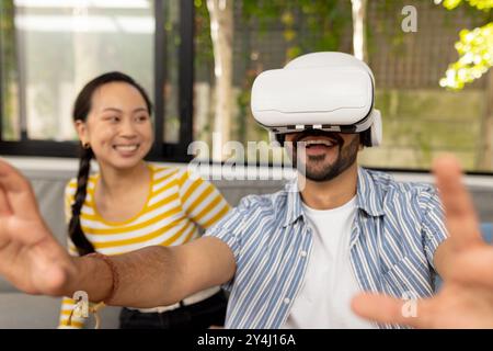 Using VR headset, man experiencing virtual reality while woman smiling nearby Stock Photo