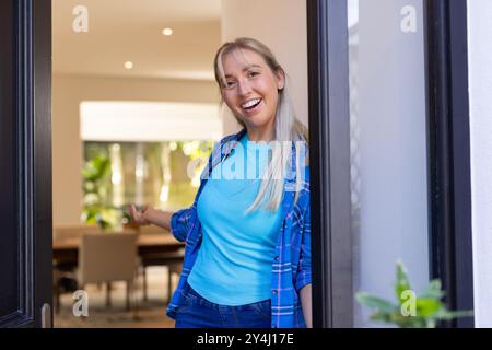 Welcoming friends into home, smiling woman standing in doorway, copy space Stock Photo
