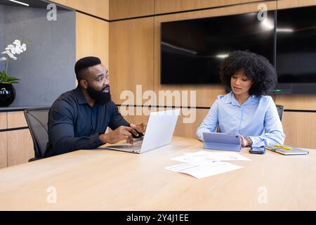 Business meeting, man using laptop and woman taking notes on tablet in office Stock Photo
