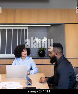 Business meeting, colleagues discussing project at table with laptop and documents Stock Photo