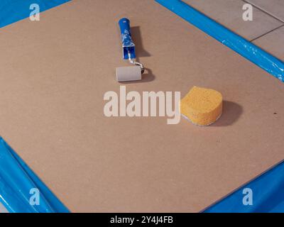 a paint roller and a yellow sponge lie on the board ready to use, photos from above Stock Photo