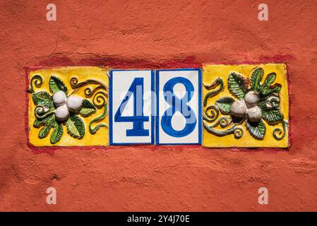 House number 48, displayed in blue and white, features Spanish-style tiles against a terracotta wall. Stock Photo