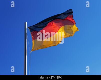German national flag in strong wind against blue sky Stock Photo