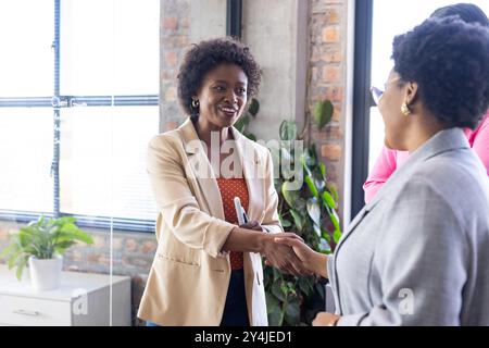 Shaking hands with colleague, businesswoman smiling and building connections in office Stock Photo