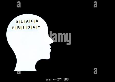 White silhouette of a human head with the words “Black Friday” spelled out with letter tiles inside the head. The composition is set against a black b Stock Photo