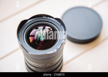 Wide angle lens resting on white wood surface with lens cap off camera Stock Photo