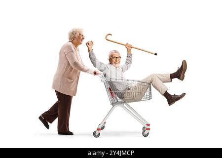 Elderly woman pushing an elderly man inside a shopping cart isolated on white background Stock Photo