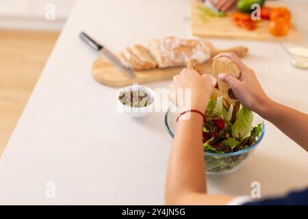 Preparing fresh salad, person mixing vegetables in glass bowl on kitchen counter, copy space Stock Photo