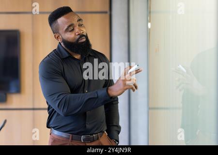 Business professional writing on whiteboard during meeting in office setting Stock Photo