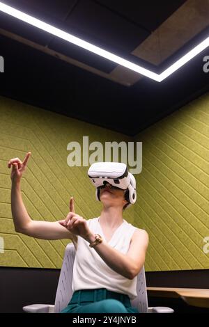 Using VR headset, businesswoman interacting with virtual environment in office Stock Photo