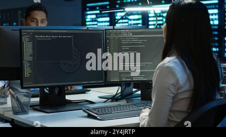 Team of technicians in data center designing, implementing and managing infrastructure to ensure optimal performance and reliability. Teamworking colleagues in server room coding on computer, camera A Stock Photo
