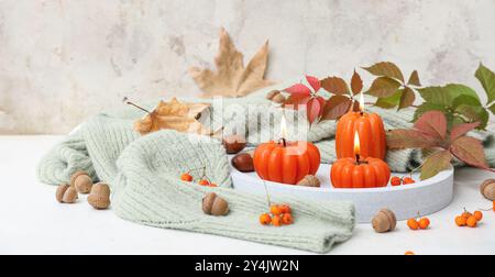 Beautiful autumn composition with burning candles in shape of pumpkins on light background Stock Photo