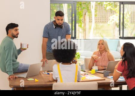 Start up business, collaborating on project, group of friends using laptops and discussing ideas Stock Photo