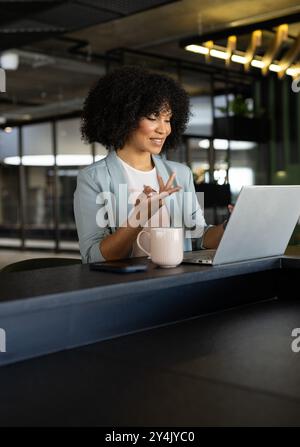 Working on laptop, businesswoman in office having video call with coffee mug nearby Stock Photo