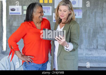Smiling multiracial senior female colleagues using tablet while discussing project in modern office Stock Photo