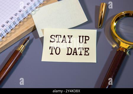 Stay Up To Date. text. Notepad, white sticker and pensil on the desk. Stock Photo