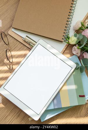 The workspace is organized with a tablet, glasses, stationery, and green foliage, all arranged harmoniously to create a tranquil atmosphere for focus Stock Photo