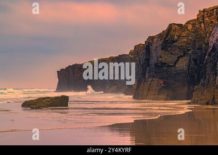 Sunset on the beach of Praia das Catedrais (Playa de las Catedrales). Along the northwest coast of Spain there are many beautiful rock formations. Pla Stock Photo