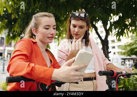 Women Engaging in Conversation While Looking at Smartphone Stock Photo